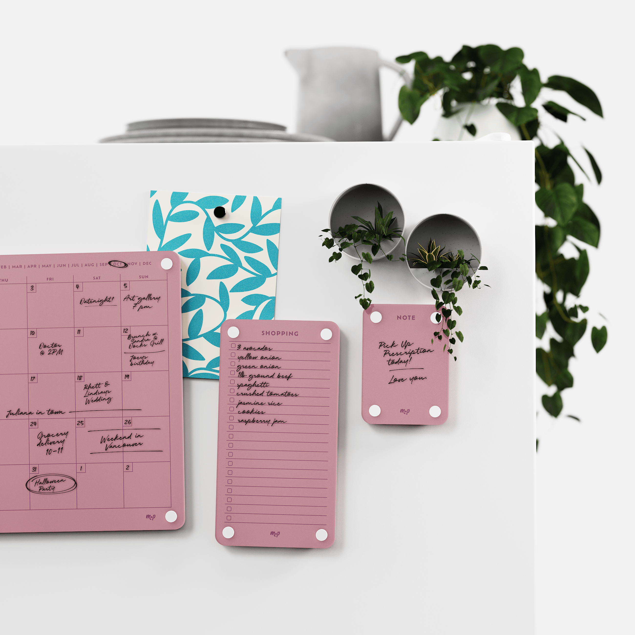 Plum monthly calendar, shopping list and note board on a white kitchen wall with magnetic planters